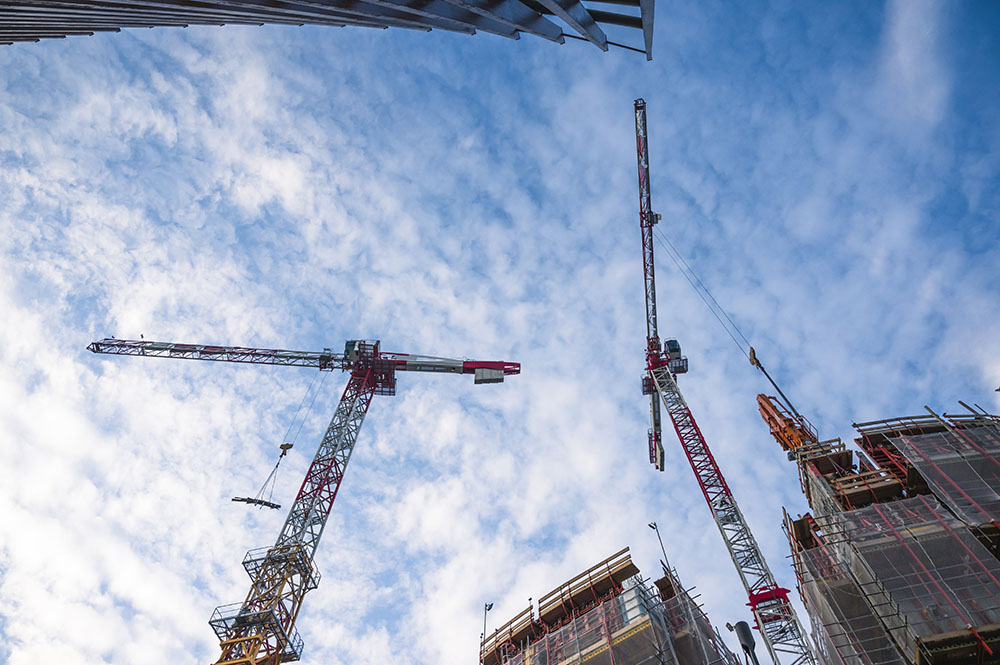 Upward shot of construction cranes against a blue sky