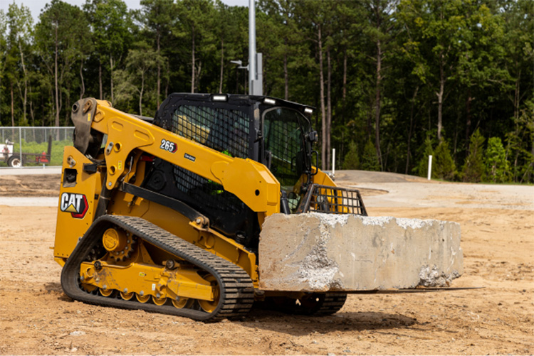 Cat CTL moving large stone on a fork attachment