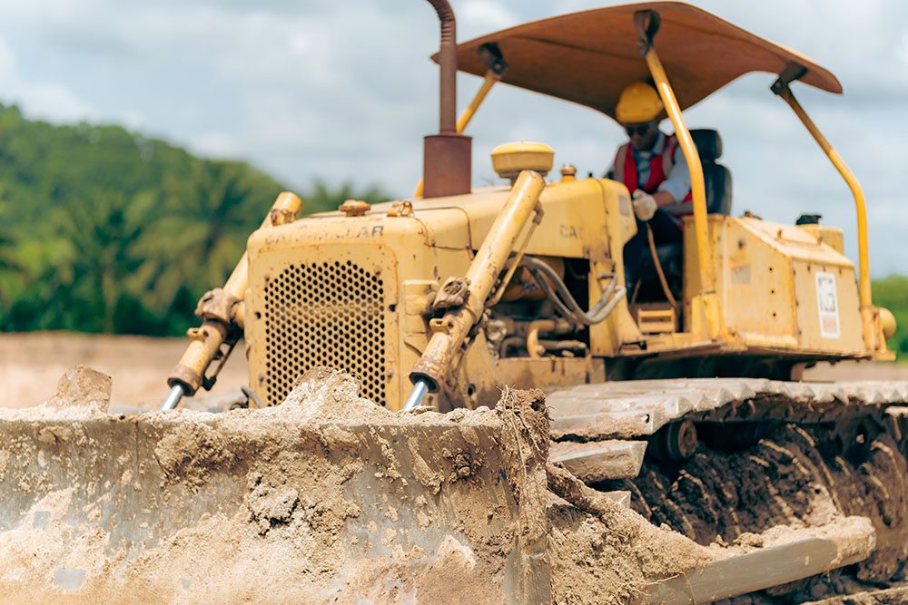 construction worker operating a bulldozer with hydraulic cylinders
