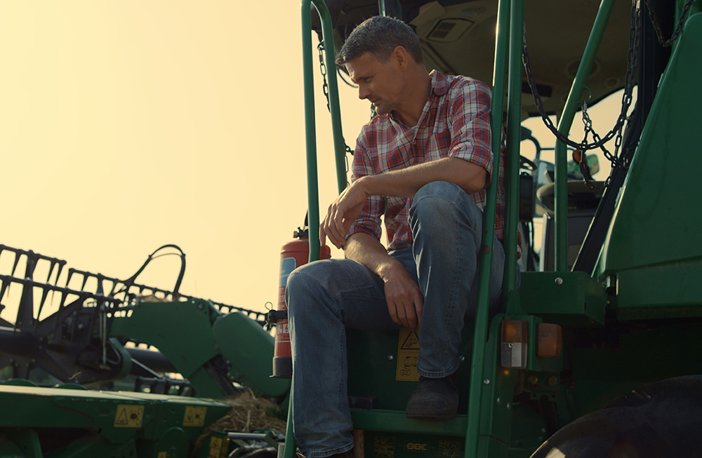 Farmer looking contemplative while sitting in John Deere tractor