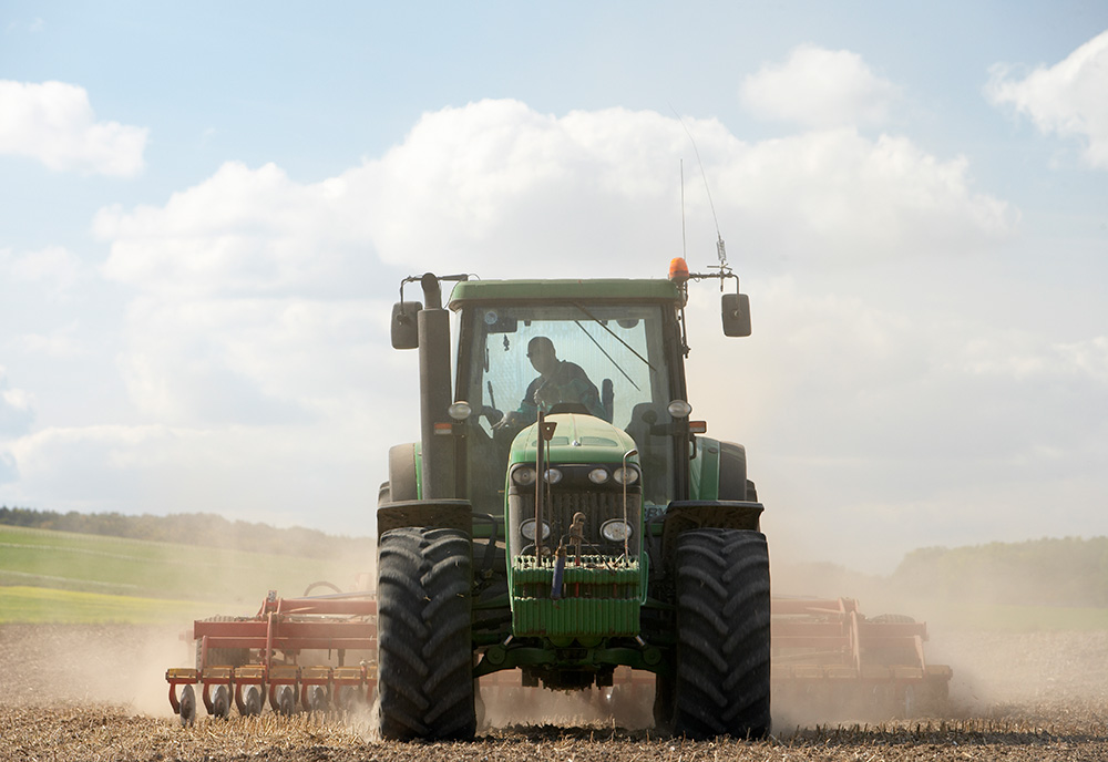 Shot of John Deere tractor working in dusty field