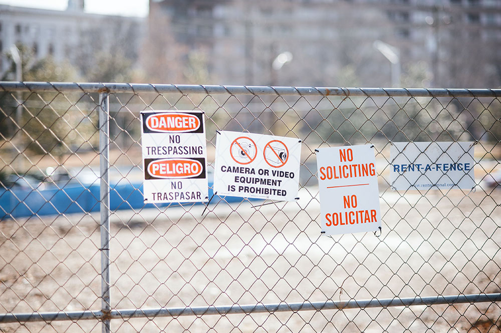 Wire fence around a jobsite with multiple warning signs against theft