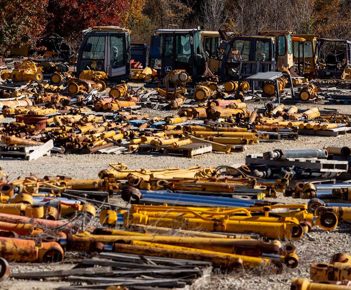Deere salvage yard filled with hydraulic cylinders and excavator cabs